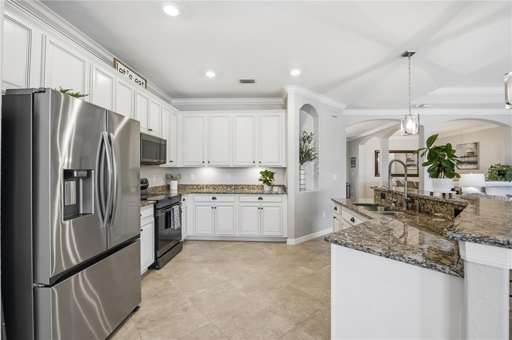A kitchen with white cabinets, granite countertops, stainless steel appliances, and tile flooring — 13834 VANCANZA DRIVE, VENICE, FL