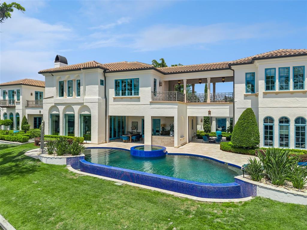 A Mediterranean-style house features a tiled roof, a stone-arched entryway, and a paved driveway — 9236 BAY POINT DRIVE, ORLANDO, FL