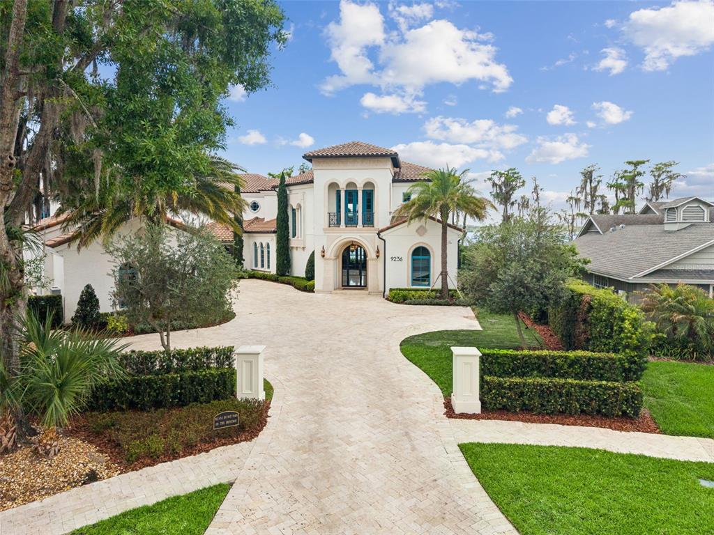A grand foyer features a marble floor, a floating staircase, and a large modern chandelier — 9236 BAY POINT DRIVE, ORLANDO, FL