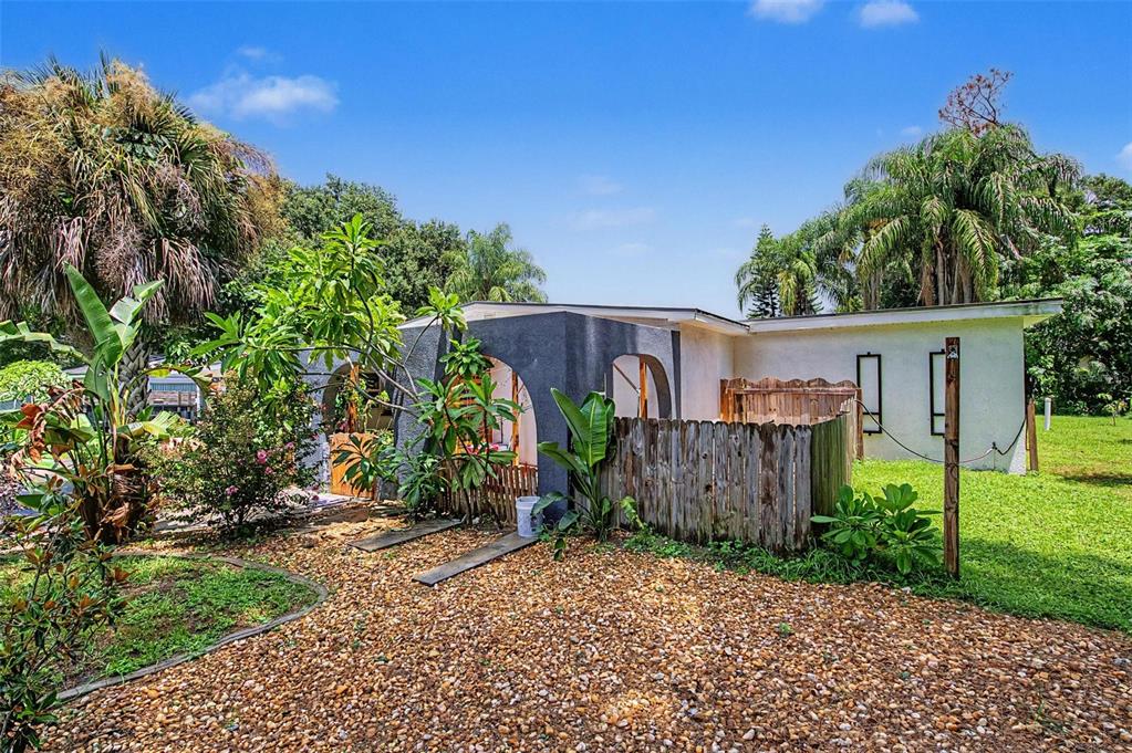 A single-story house with a gravel yard, wooden fence, and arched entryway — 2767 BELLE HAVEN DRIVE, CLEARWATER, FL