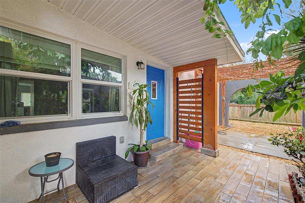 A covered patio with wood-look tile flooring, a blue front door, and a wooden privacy screen — 2767 BELLE HAVEN DRIVE, CLEARWATER, FL