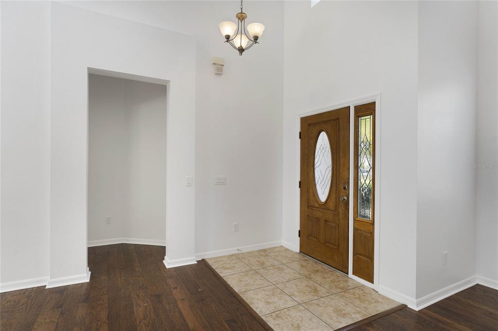 An entryway features a wood front door, tiled floor, and a high ceiling with a chandelier — 5270 RISHLEY RUN WAY, MOUNT DORA, FL