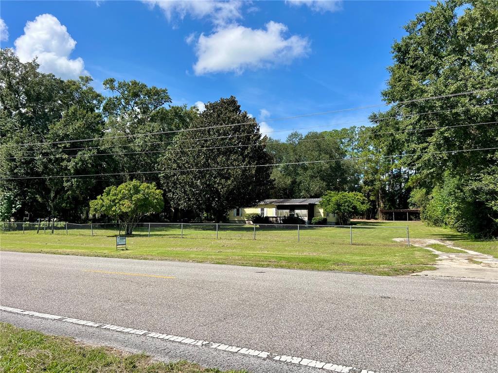 A gravel driveway leads to a fenced yard with a house and a parked truck — 11820 NW HIGHWAY 225, REDDICK, FL