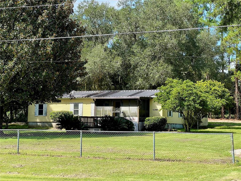 A backyard view showing a yellow house, a small shed, and large trees — 11820 NW HIGHWAY 225, REDDICK, FL