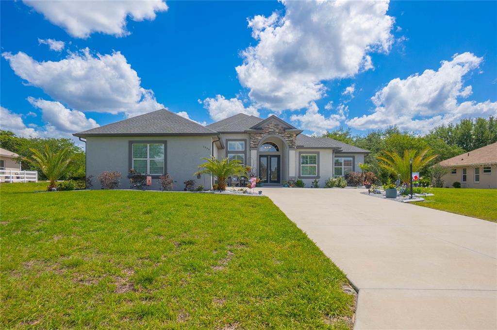 A single-story house with a gray exterior, a hip roof, and a landscaped front yard — 1555 E SEATTLE SLEW CIRCLE, INVERNESS, FL