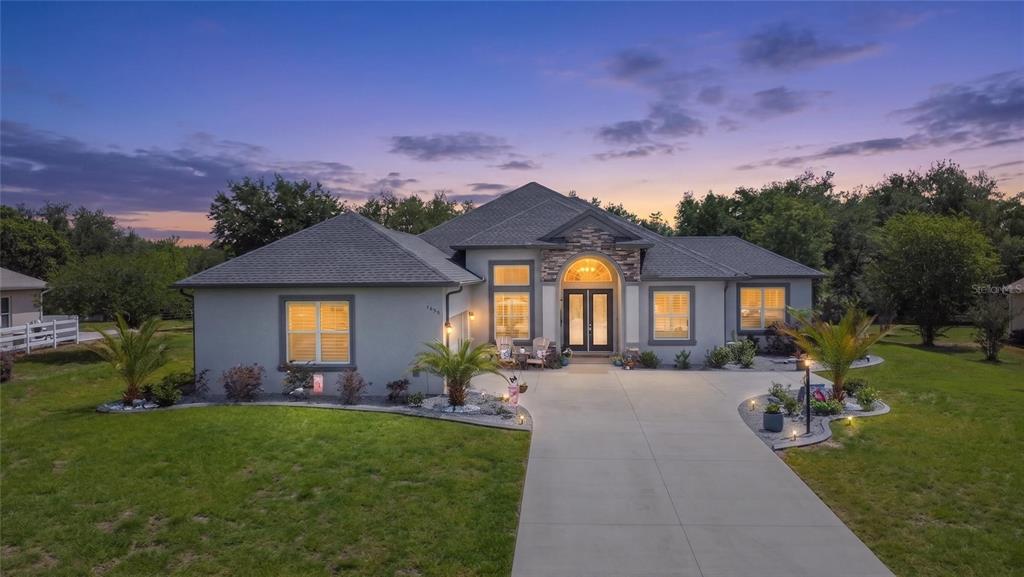A single-story suburban house with a stone-accented entryway, a two-car garage, and a landscaped yard — 1555 E SEATTLE SLEW CIRCLE, INVERNESS, FL