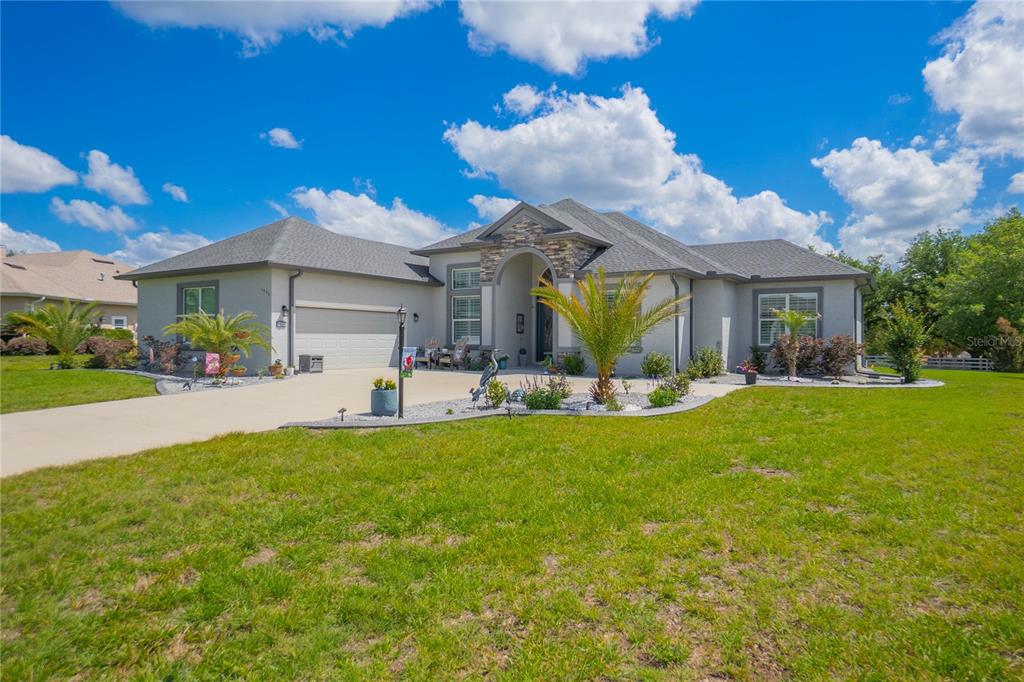 A single-story house with a stone-accented entryway, a two-car garage, and a landscaped front yard — 1555 E SEATTLE SLEW CIRCLE, INVERNESS, FL