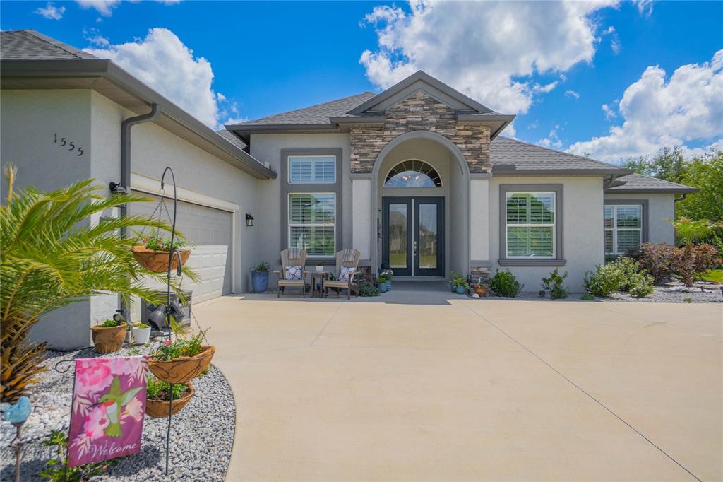 A single-story house with a stone-accented entryway, double front doors, and a concrete driveway — 1555 E SEATTLE SLEW CIRCLE, INVERNESS, FL