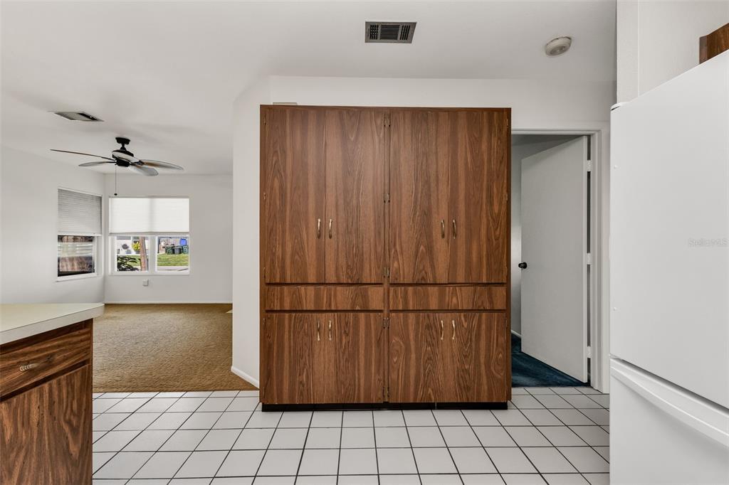 A kitchen with white tile flooring and a large wood-grain storage cabinet — 4100 GROBE STREET, NORTH PORT, FL