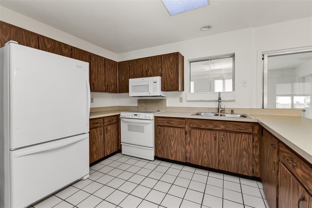A kitchen features wood cabinets, white appliances, a tiled floor, and a window over the sink — 4100 GROBE STREET, NORTH PORT, FL