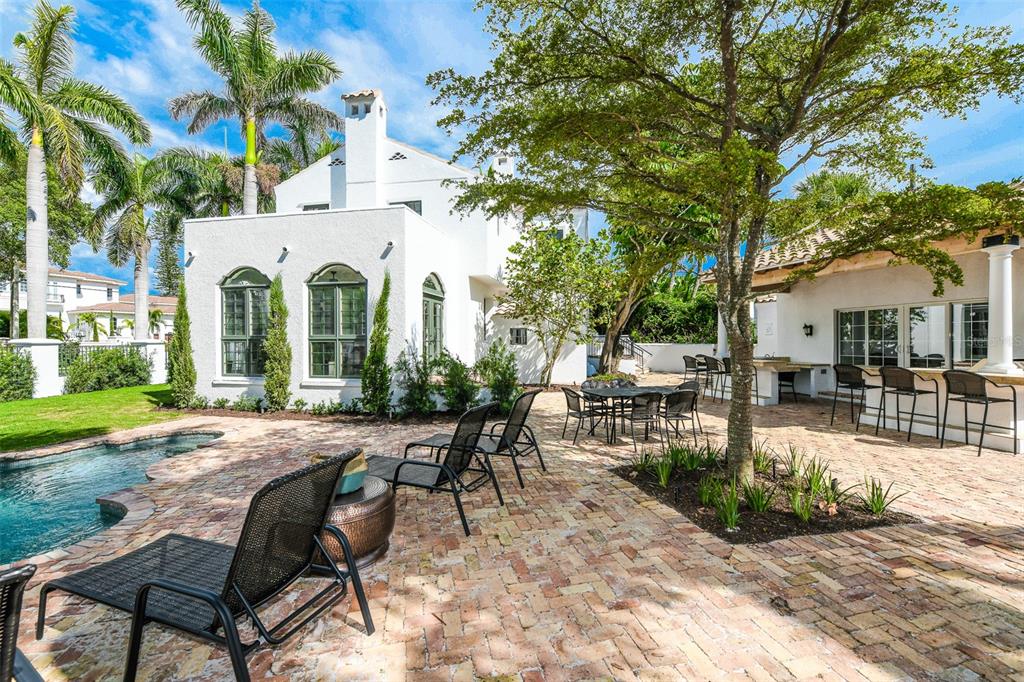 A backyard patio features a swimming pool, brick pavers, outdoor seating, and a white house — 76 S WASHINGTON DRIVE, SARASOTA, FL