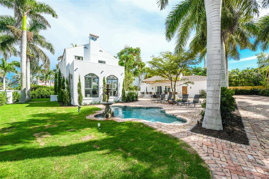 A white house with a pool, fountain, and palm trees in a landscaped backyard — 76 S WASHINGTON DRIVE, SARASOTA, FL