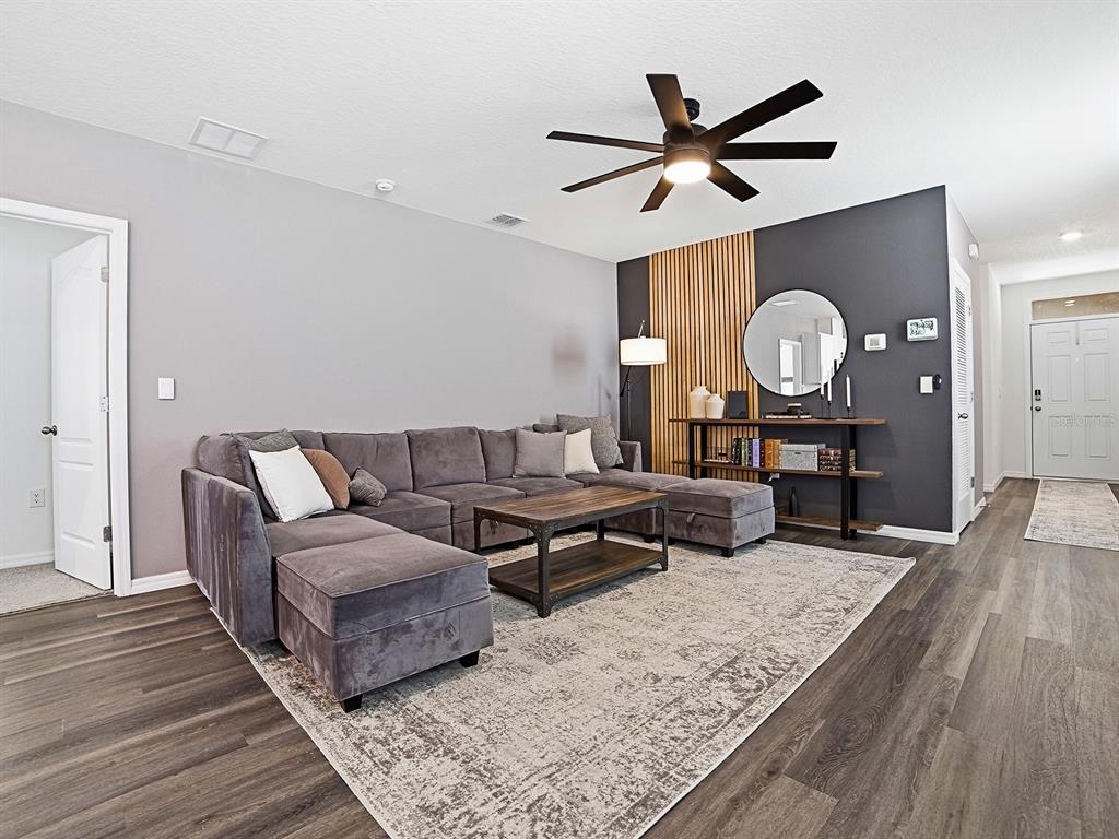 A living room features a grey sectional sofa, a wood coffee table, and a slat-wall accent — 6149 GALLOPING DRIVE, APOPKA, FL