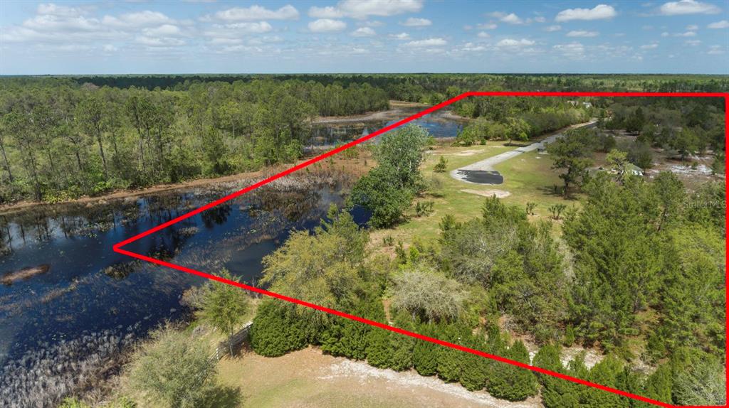 An aerial view shows a wooded lot with a large pond outlined in red — S SEQUOIA WAY, EUSTIS, FL