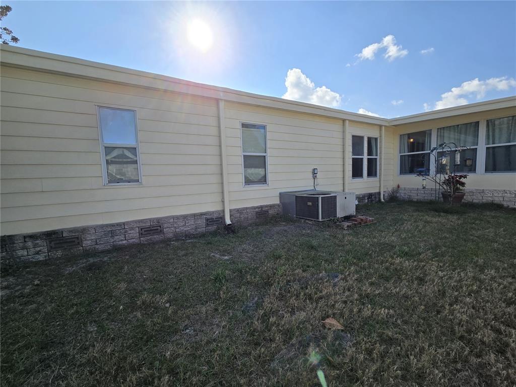 A light yellow manufactured home features a concrete driveway, a carport, and an American flag — 3450 N CITRUS CIRCLE UNIT GE, ZELLWOOD, FL