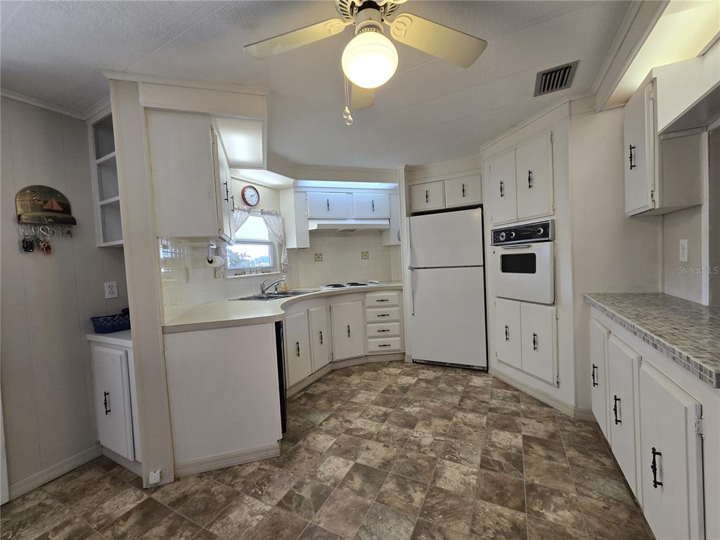 The exterior of a light yellow manufactured home with a brick-patterned skirting and AC unit — 3450 N CITRUS CIRCLE UNIT GE, ZELLWOOD, FL