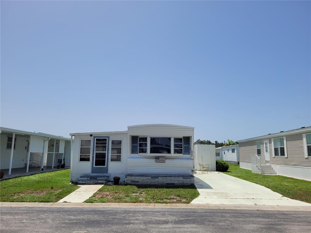 A single-story mobile home with white siding, a front porch, and a concrete driveway — 3332 SPANISH OAK TERRACE, SARASOTA, FL