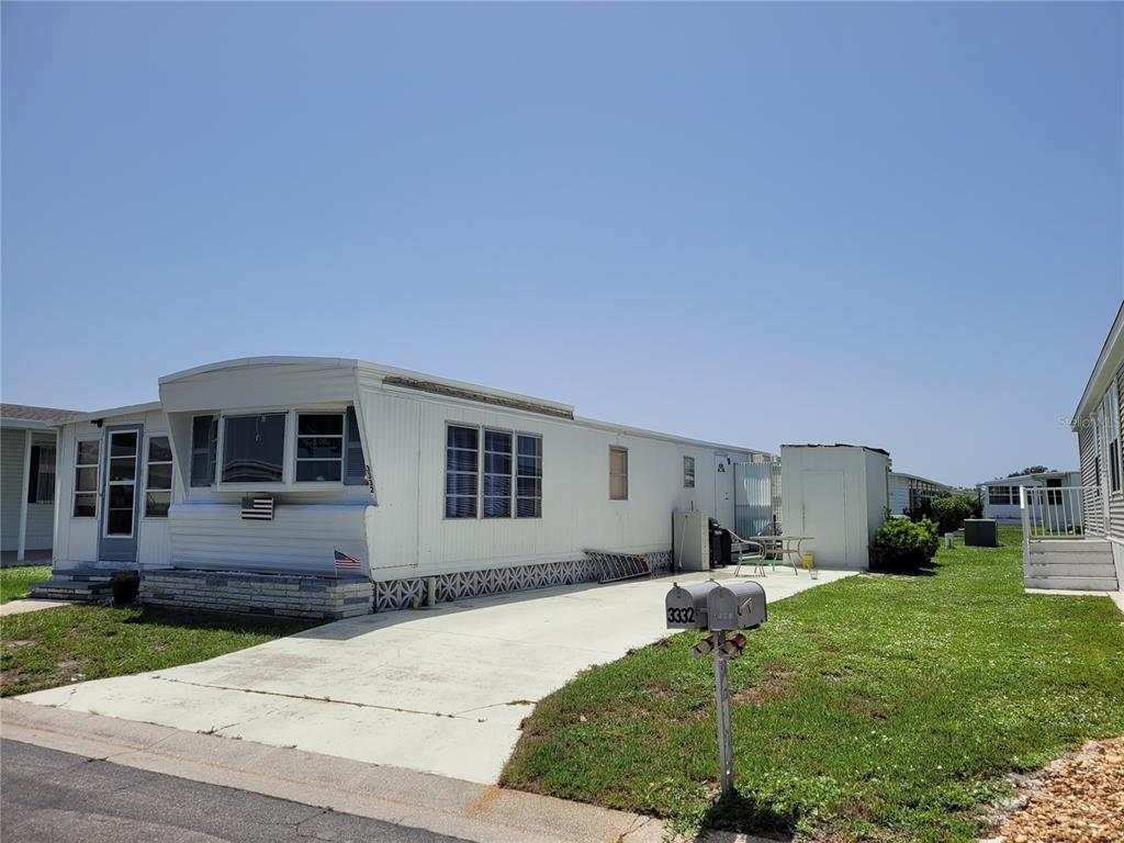 A single-story mobile home with white siding, a concrete driveway, and a mailbox in front — 3332 SPANISH OAK TERRACE, SARASOTA, FL