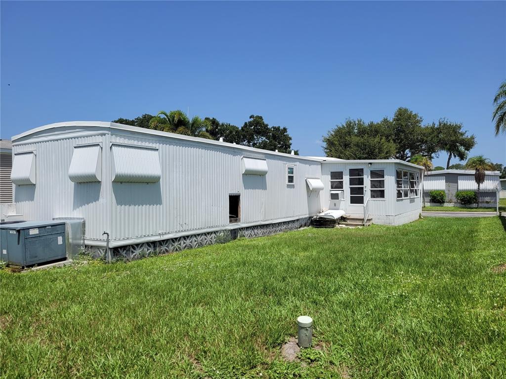 The exterior of a white mobile home with a screened-in porch and a grassy yard — 3332 SPANISH OAK TERRACE, SARASOTA, FL