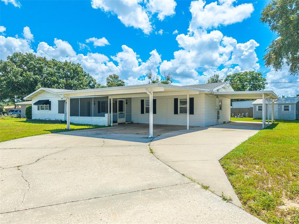 A single-story white house with a large concrete driveway and a covered carport — 1380 S LAKE ROY DRIVE, WINTER HAVEN, FL