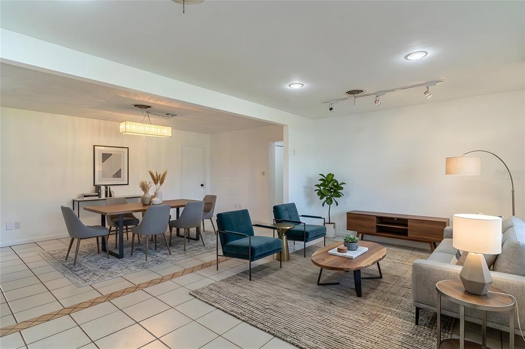 An open-concept living and dining area features tiled floors, area rugs, and modern furniture — 1380 S LAKE ROY DRIVE, WINTER HAVEN, FL