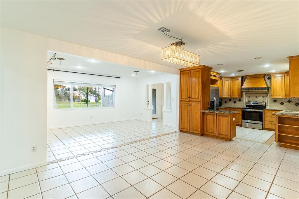 A bright kitchen and dining area with light-colored tile floors and wood cabinetry — 1380 S LAKE ROY DRIVE, WINTER HAVEN, FL