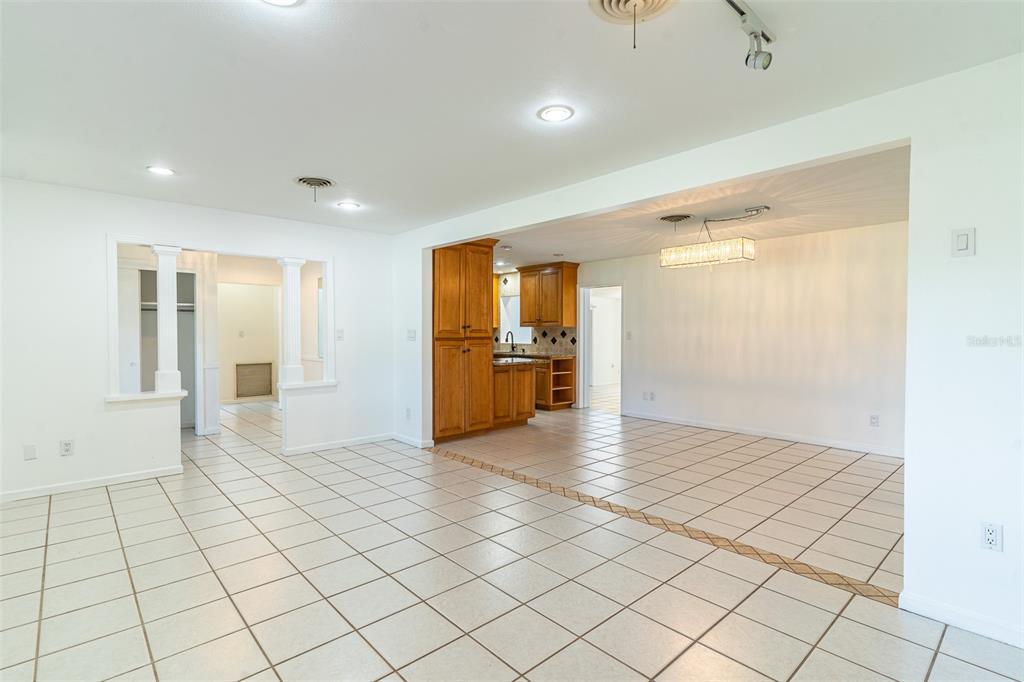An open-concept living and dining area features white walls, tiled floors, and wooden kitchen cabinets — 1380 S LAKE ROY DRIVE, WINTER HAVEN, FL