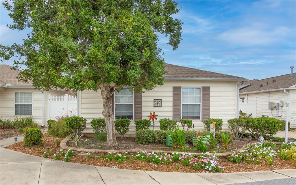 A single-story house with a large tree, a concrete driveway, and a parked golf cart — 7618 SE 171ST SUN VALLEY PLACE, THE VILLAGES, FL