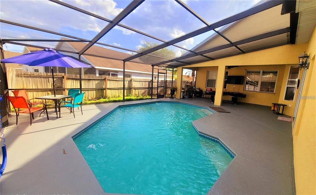 A screened-in patio features a swimming pool, outdoor dining area, and a covered lounge space — 10 NEVADA LOOP ROAD, DAVENPORT, FL