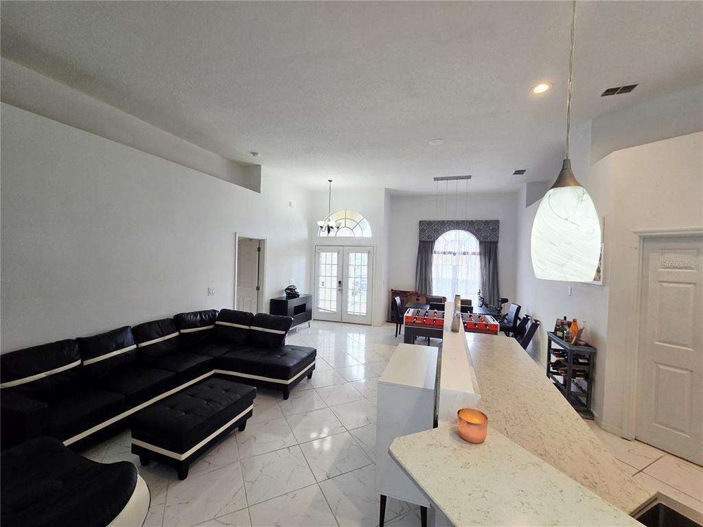 A swimming pool sits on a patio enclosed by a screened lanai behind a house — 10 NEVADA LOOP ROAD, DAVENPORT, FL