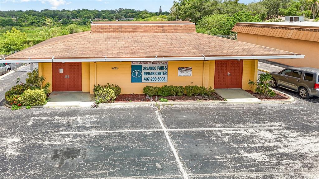 A single-story commercial building with a brown shingled roof and two red double doors — 6005 SILVER STAR ROAD, ORLANDO, FL