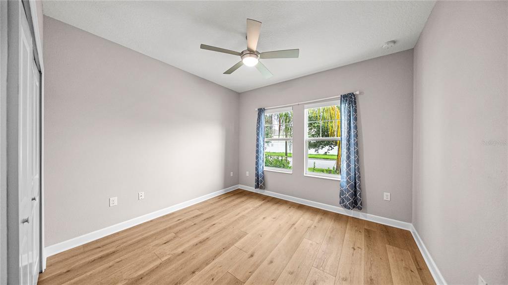 An open-concept living room and kitchen featuring brown leather sofas, wood flooring, and white cabinetry — 10264 LOVE STORY STREET, WINTER GARDEN, FL