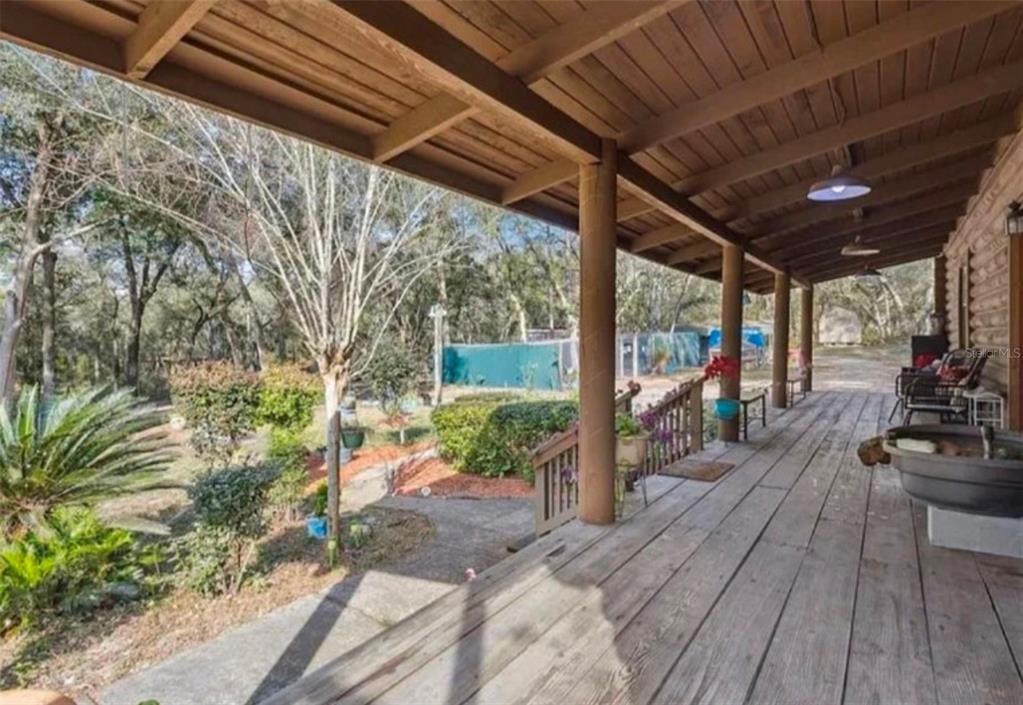 A wide wooden porch overlooks a landscaped yard with trees and a fenced area — 1208 DARCY ROAD, LADY LAKE, FL