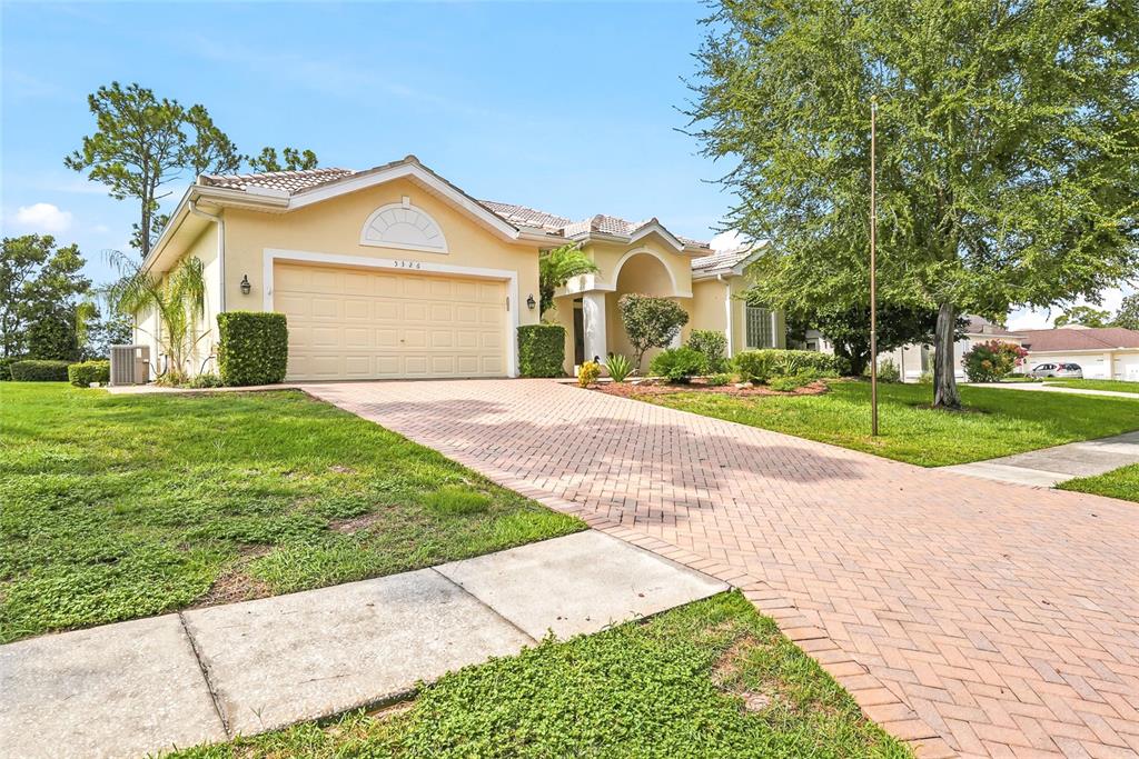 A single-story house with a yellow exterior, a brick driveway, and a two-car garage — 5326 LEGEND HILLS LANE, SPRING HILL, FL