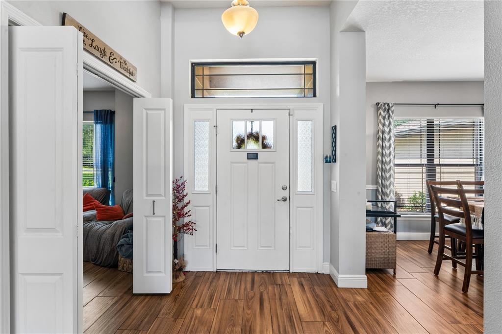 A bright entryway features wood-look tile flooring, a white front door with sidelights, and high ceilings — 27725 CENTURY OAKS COURT, DADE CITY, FL