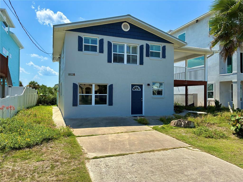 A two-story house with a light gray exterior, dark blue shutters, and a concrete driveway — 1828 S CENTRAL AVENUE, FLAGLER BEACH, FL
