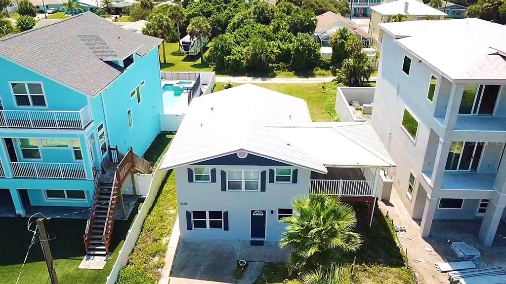 An aerial view shows a light-colored house situated between two taller, multi-story residential buildings — 1828 S CENTRAL AVENUE, FLAGLER BEACH, FL