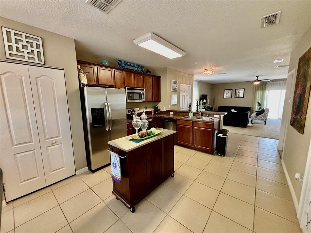 A kitchen with dark wood cabinets and a breakfast bar overlooks a dining area — 1861 CHATHAM PLACE DRIVE, ORLANDO, FL