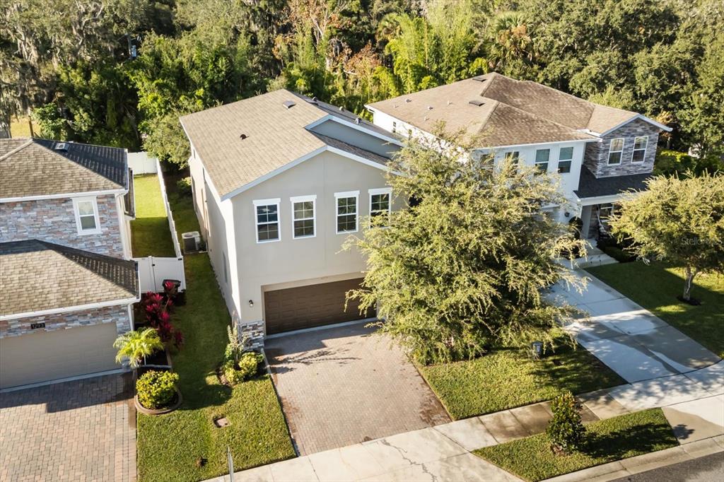 An aerial view shows the exterior of a two-story beige house with a paved driveway — 1289 ASH TREE COVE, CASSELBERRY, FL