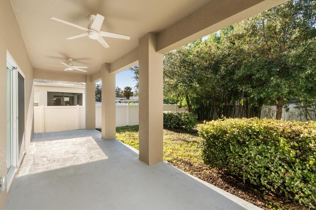 A covered concrete patio features two ceiling fans and views of a landscaped backyard — 1289 ASH TREE COVE, CASSELBERRY, FL