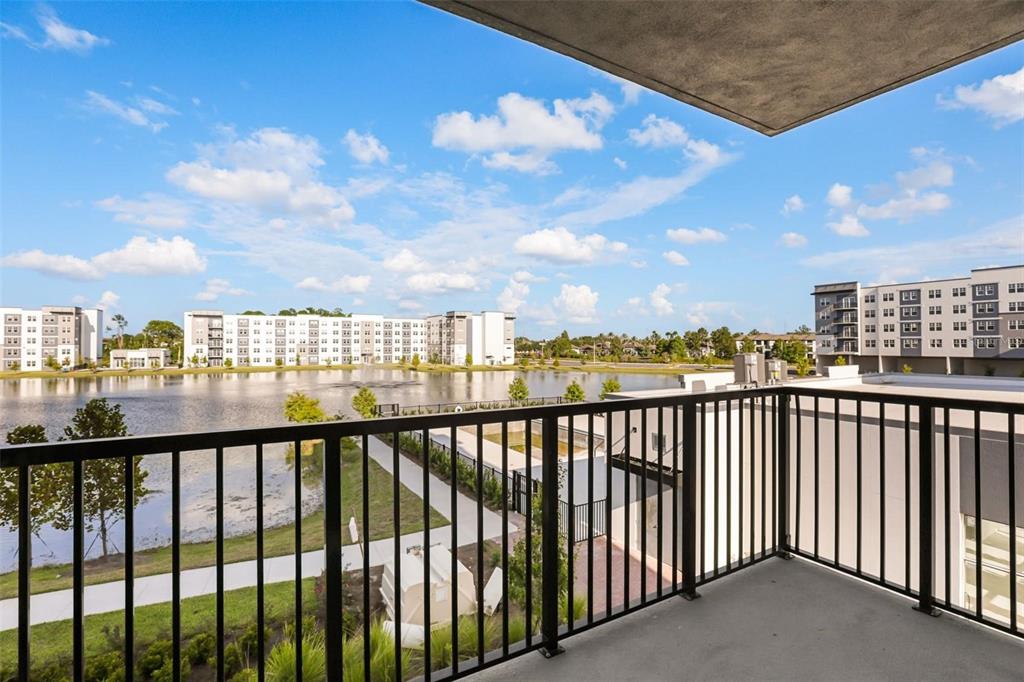 A balcony with a black metal railing overlooks a lake and nearby apartment buildings — 5563 MILLENIA PARK BOULEVARD UNIT 225, ORLANDO, FL