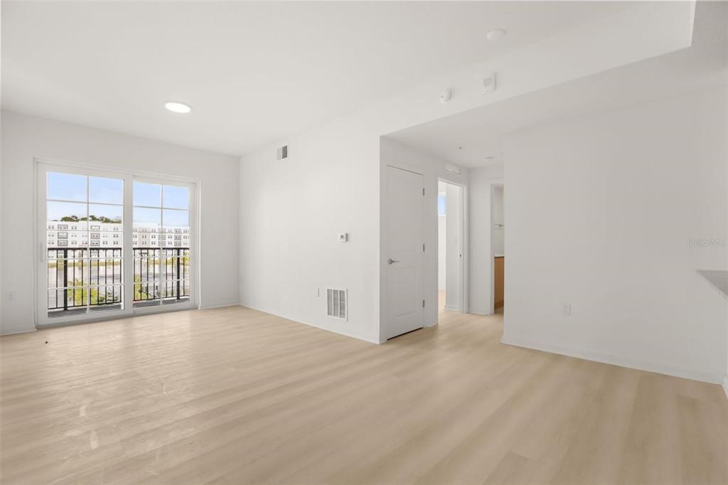 An empty room with light wood-look flooring, white walls, and a sliding glass balcony door — 5563 MILLENIA PARK BOULEVARD UNIT 225, ORLANDO, FL