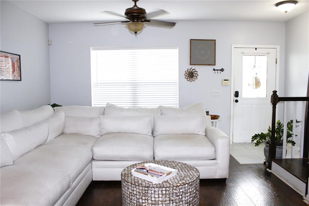 A living room features a large white sectional sofa, a round textured coffee table, and decor — 5307 TERRAZA COURT, TEMPLE TERRACE, FL