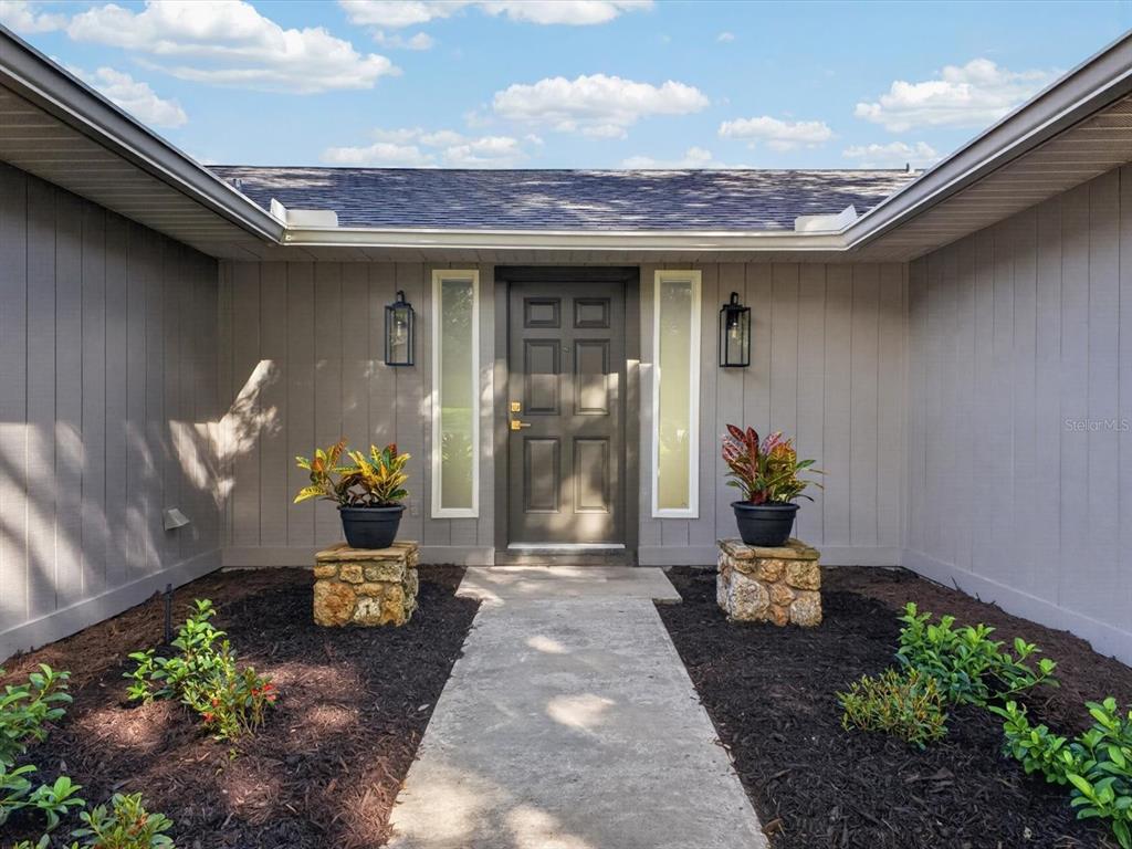 A front entryway features a gray door, two side windows, and potted plants on stone pedestals — 2183 BENT OAK DRIVE, APOPKA, FL