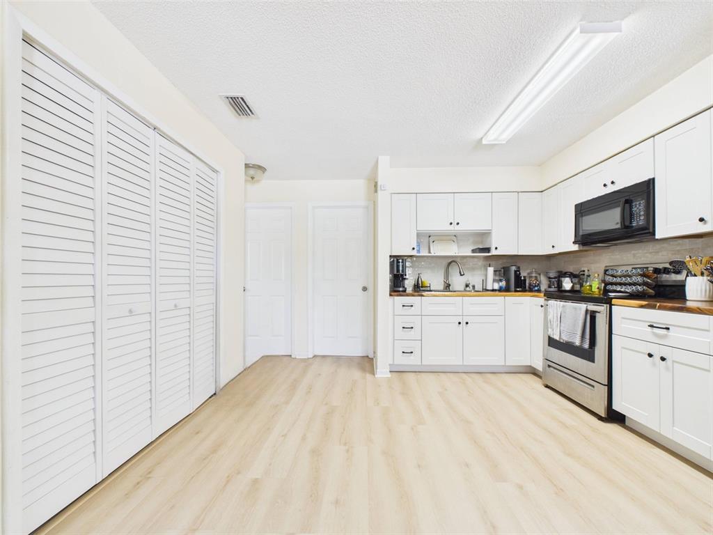 A kitchen with white cabinets, stainless steel appliances, and light wood-look flooring — 1411 E 109TH AVENUE UNIT B, TAMPA, FL