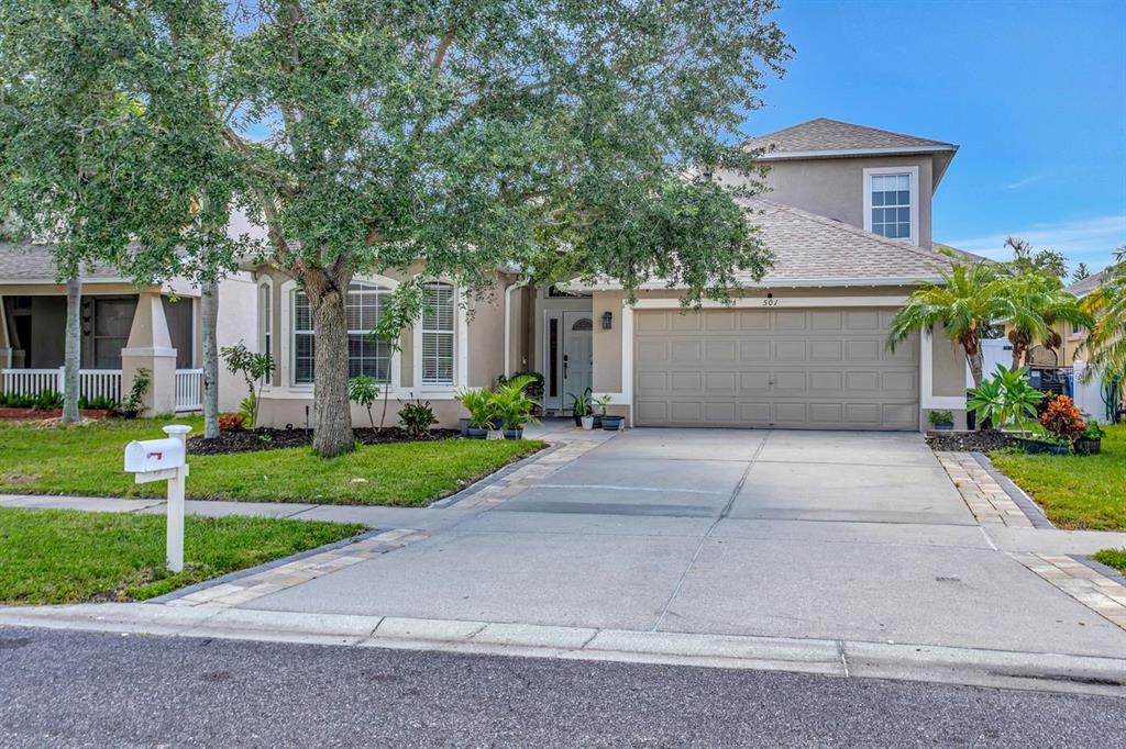 A two-story suburban house with a beige exterior, a two-car garage, and a paved driveway — 501 STONE BRIAR DRIVE, RUSKIN, FL