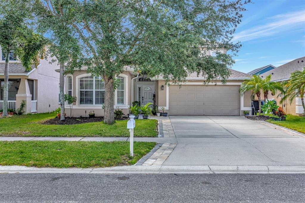 A single-story suburban house with a tan exterior, a two-car garage, and a large front tree — 501 STONE BRIAR DRIVE, RUSKIN, FL