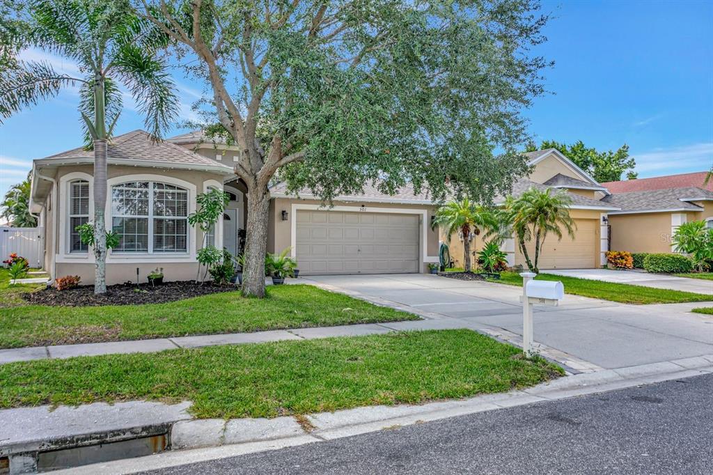 A single-story suburban house with a two-car garage, a large tree, and a front lawn — 501 STONE BRIAR DRIVE, RUSKIN, FL