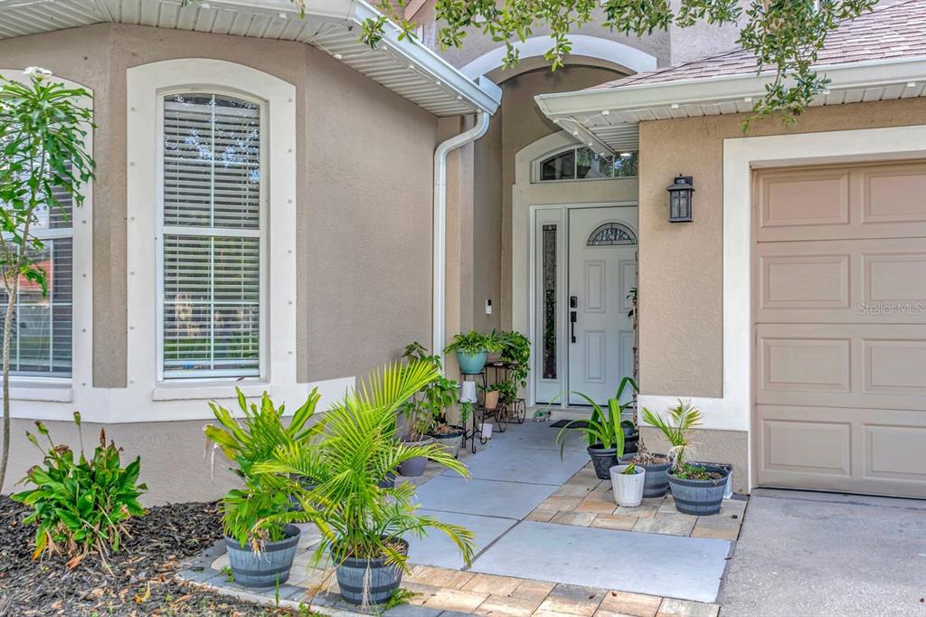 The exterior of a house features a tan stucco facade, a front door, and potted plants — 501 STONE BRIAR DRIVE, RUSKIN, FL