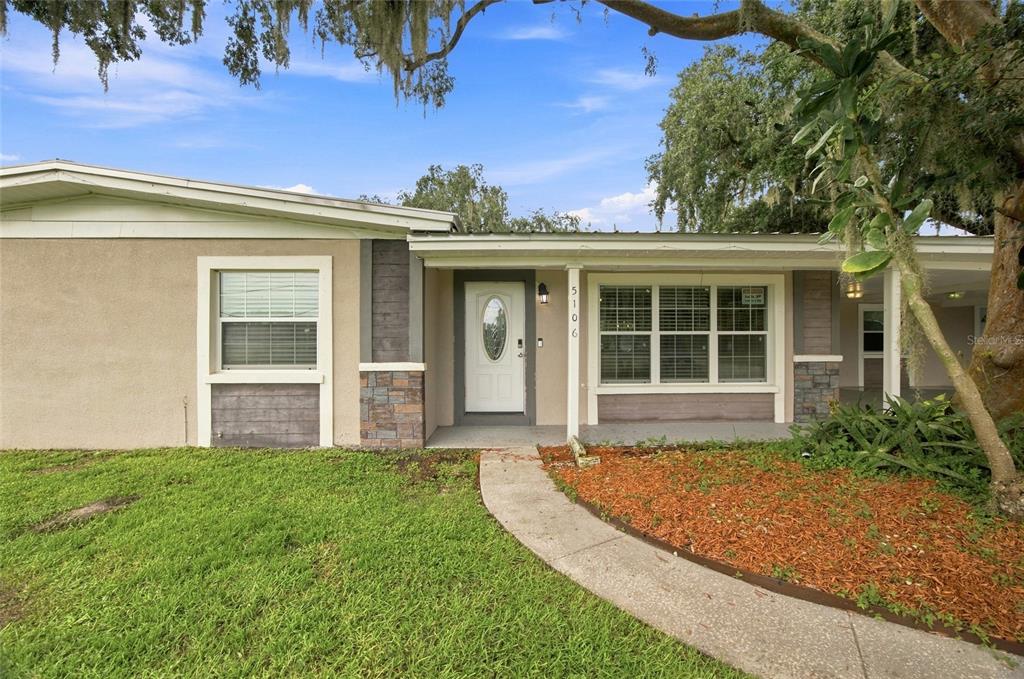 A single-story house exterior features a white front door, a large window, and stone accents — 5106 THONOTOSASSA ROAD, PLANT CITY, FL